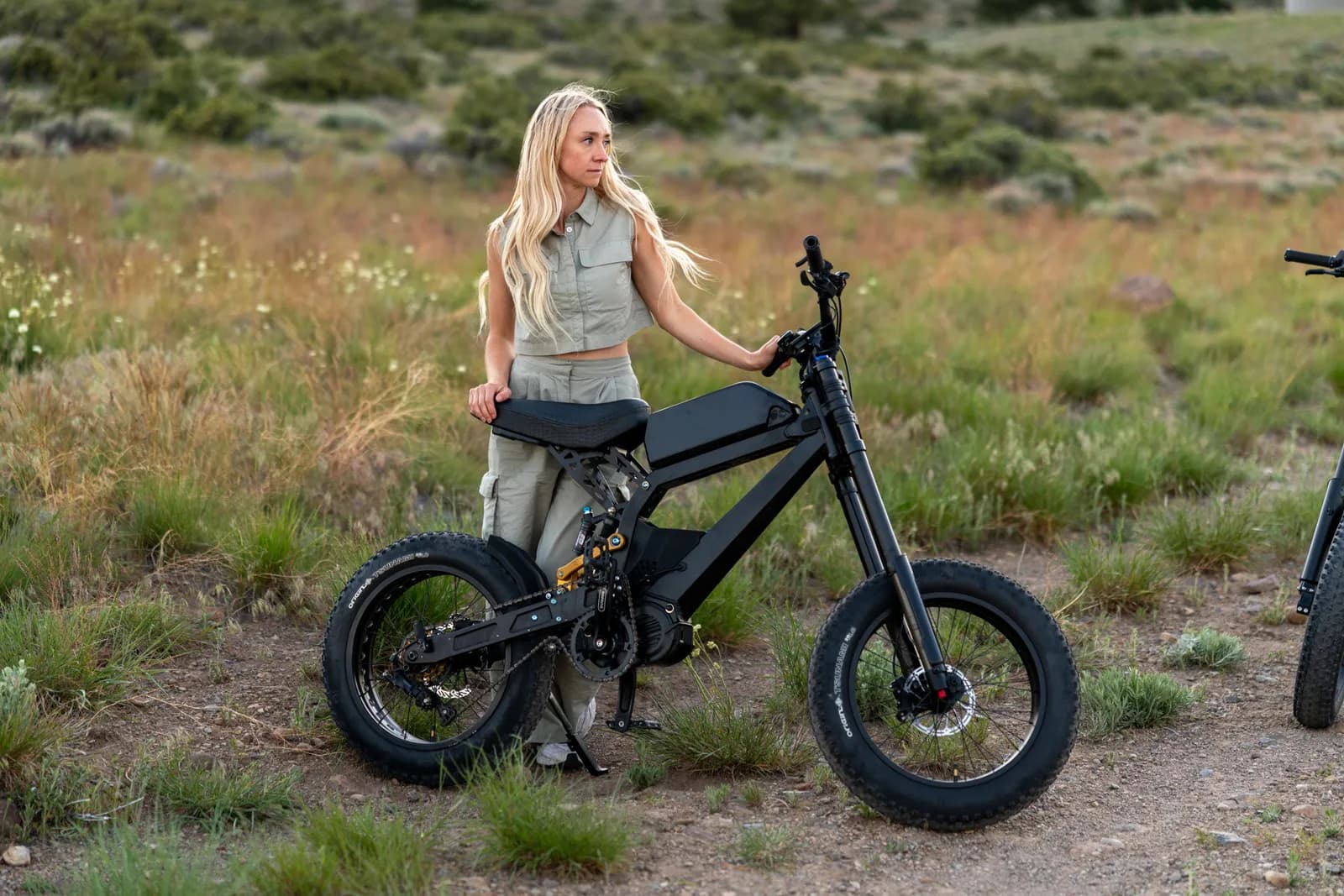 Rider beside the Surfline e-bike in a high-desert meadow